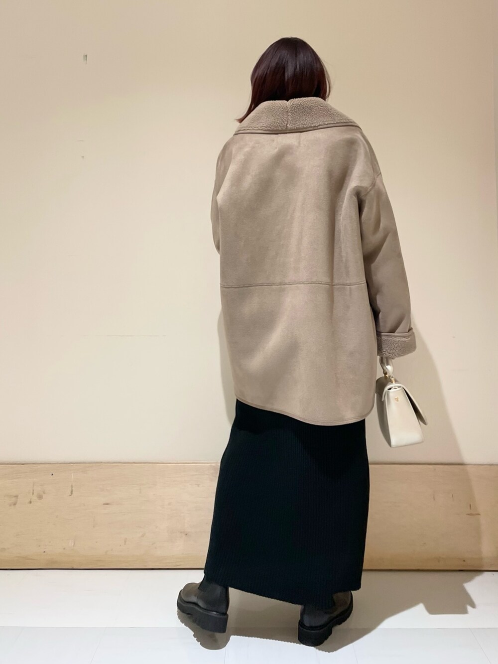 グレー系のムートンコート、ブラック系のワンピース、ゴールド系のショルダーバッグを着用したレディースの冬コーディネートの5枚目の写真