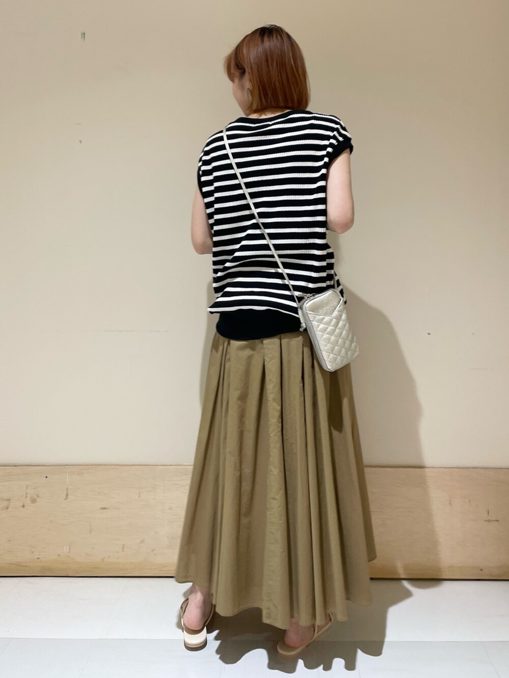 ベージュ系のスカート、ホワイト系のサンダル、ブラック系のTシャツ/カットソーを着用したレディースの夏コーディネートの6枚目の写真