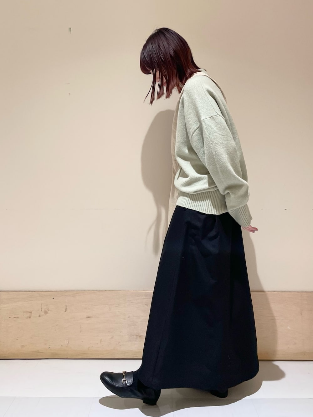 グリーン系のニット/セーター、ブラック系のスカート、グレー系のショルダーバッグを着用したレディースの冬コーディネートの5枚目の写真