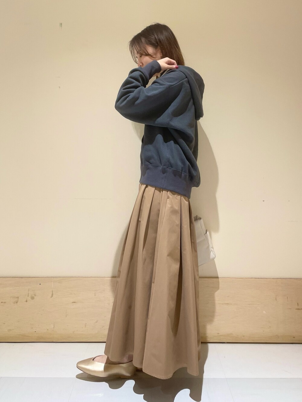 ゴールド系のパンプス、ホワイト系のトートバッグ、ベージュ系のスカートを着用したレディースの秋コーディネートの4枚目の写真