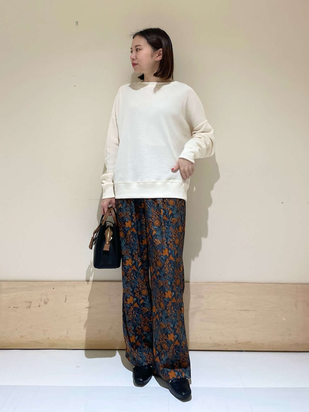 オレンジ系のその他パンツ、ブラック系のハンドバッグ、ブラック系のローファーを着用したレディースの秋コーディネートの2枚目の写真