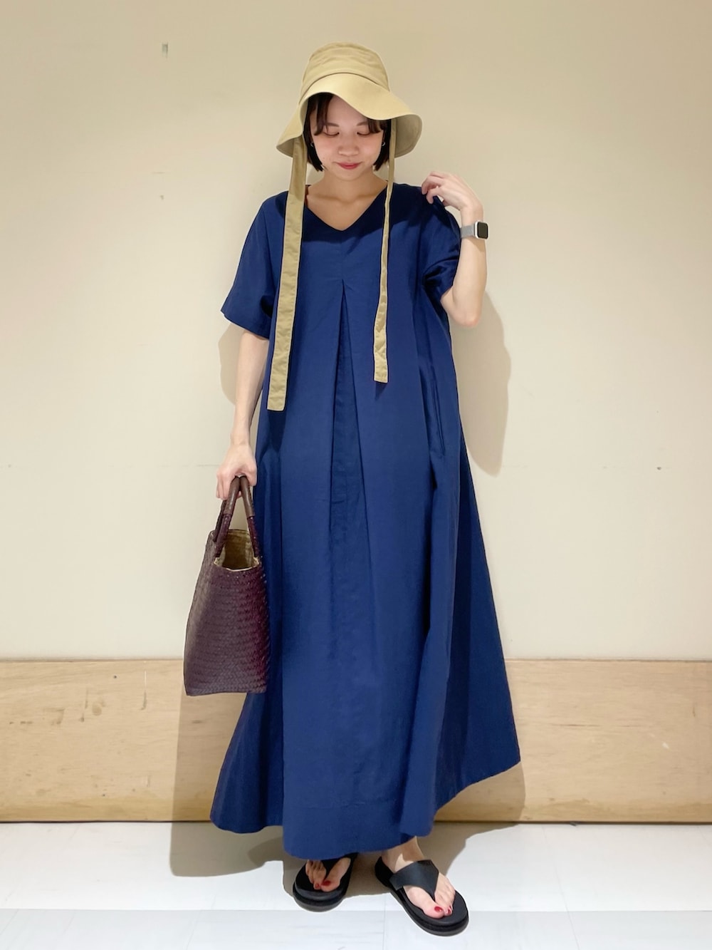 ブルー系のワンピース、ブラウン系のハンドバッグ、ブラック系のサンダルを着用したレディースの夏コーディネートの2枚目の写真