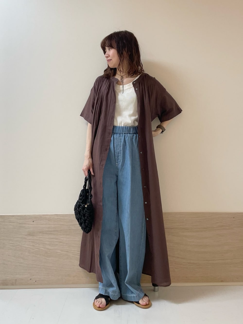 ブルー系のデニムパンツ、ブラック系のサンダル、ブラウン系のワンピースを着用したレディースの春コーディネートの4枚目の写真