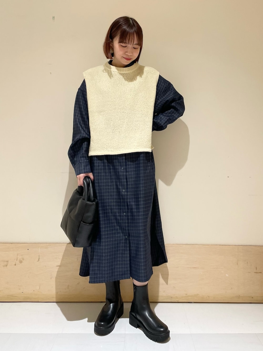 ホワイト系のベスト、グレー系のシャツワンピース、ブラック系のトートバッグを着用したレディースの秋コーディネートの3枚目の写真