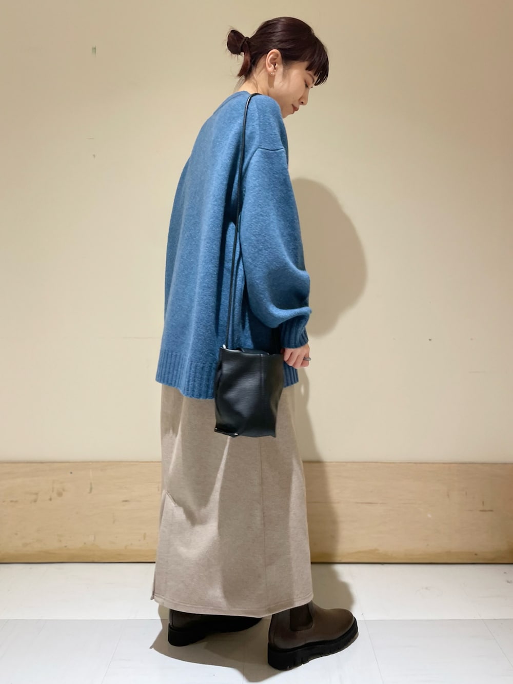ブルー系のニット/セーター、ベージュ系のスカート、ブラック系のショルダーバッグを着用したレディースの冬コーディネートの2枚目の写真