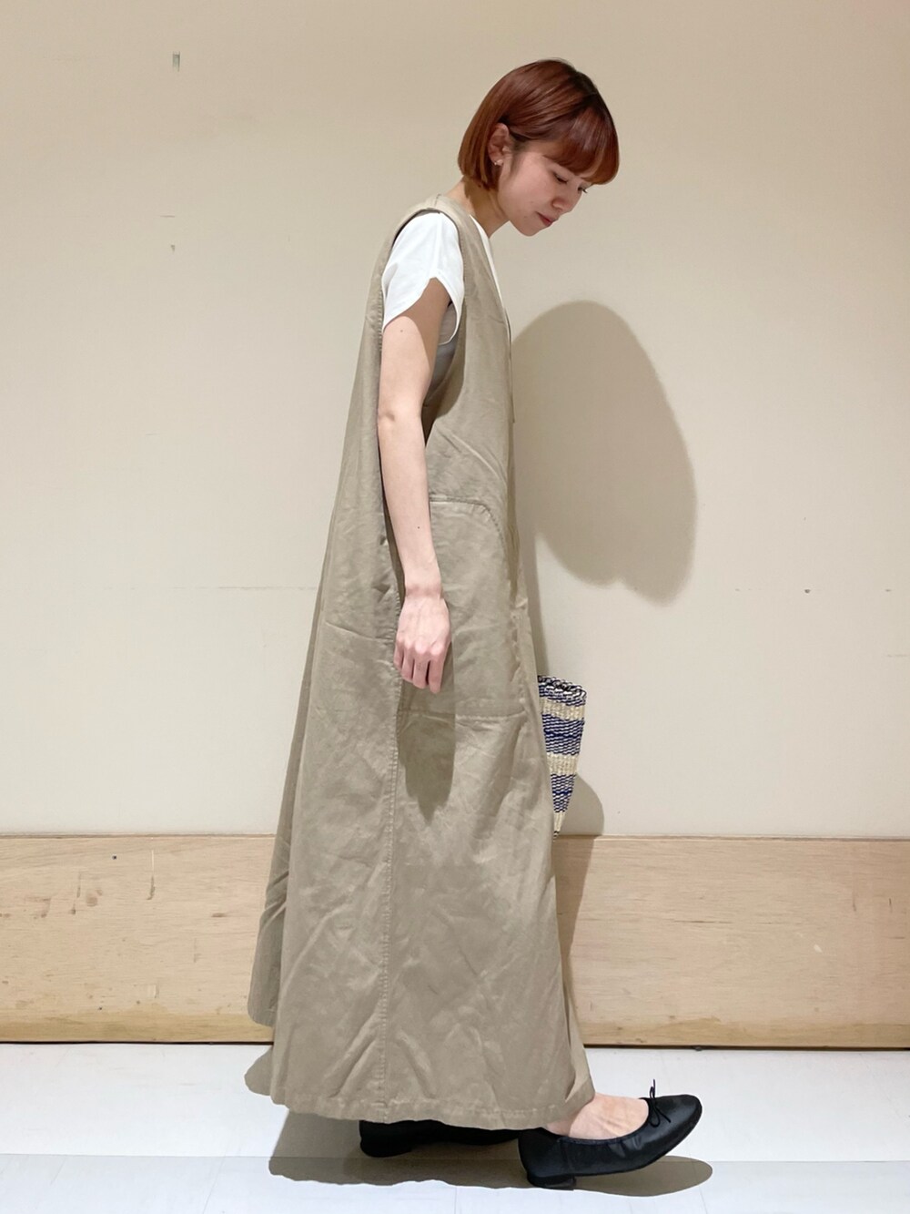 ベージュ系のワンピース、ホワイト系のTシャツ/カットソー、ブラック系のバレエシューズを着用したレディースの春コーディネートの5枚目の写真