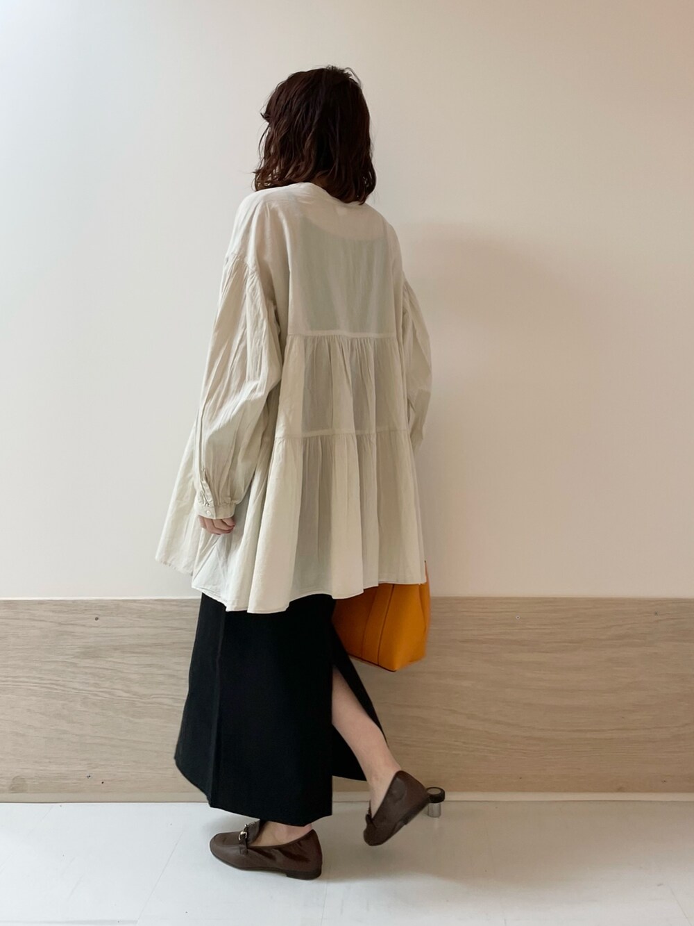 ブラック系のスカート、ホワイト系のチュニックを着用したレディースの春コーディネートの7枚目の写真