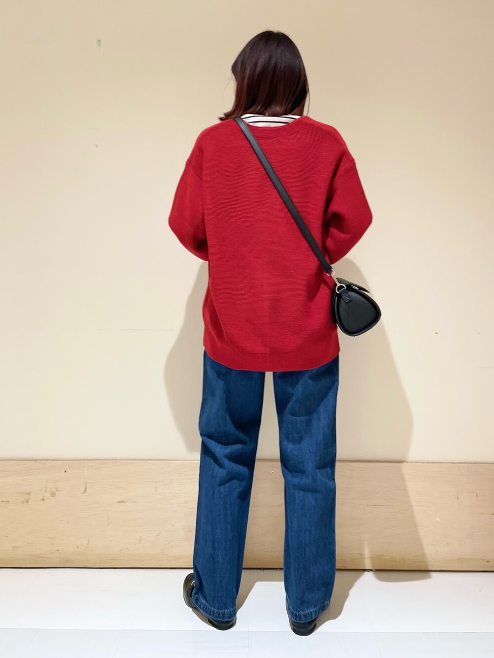 ブラック系のショルダーバッグ、レッド系のカーディガン/ボレロ、ホワイト系のTシャツ/カットソーを着用したレディースの冬コーディネートの6枚目の写真