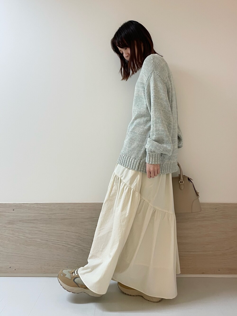 グリーン系のニット/セーター、ホワイト系のスカート、ベージュ系のスニーカーを着用したレディースの春コーディネートの5枚目の写真