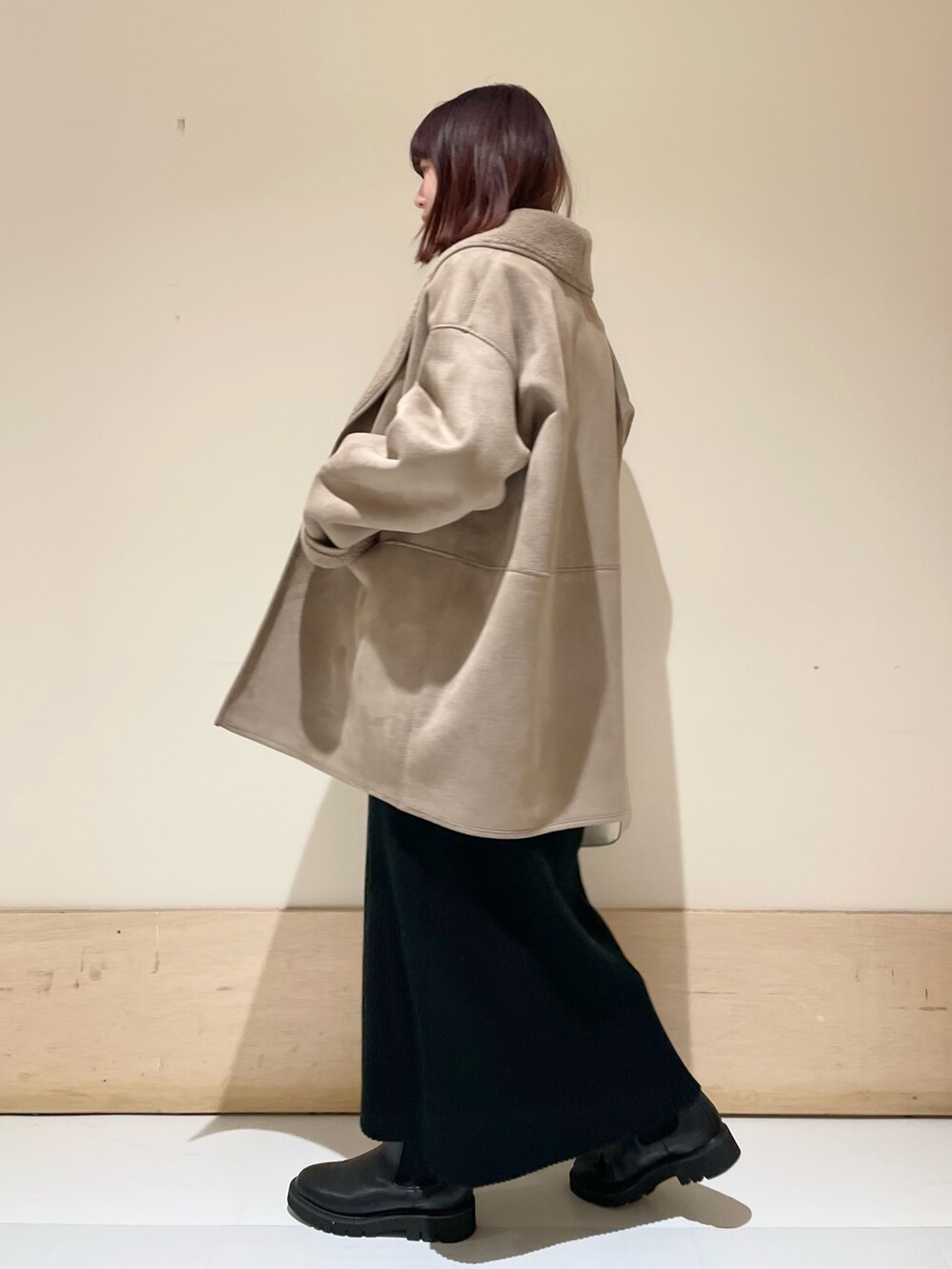 グレー系のムートンコート、ブラック系のワンピース、ゴールド系のショルダーバッグを着用したレディースの冬コーディネートの3枚目の写真