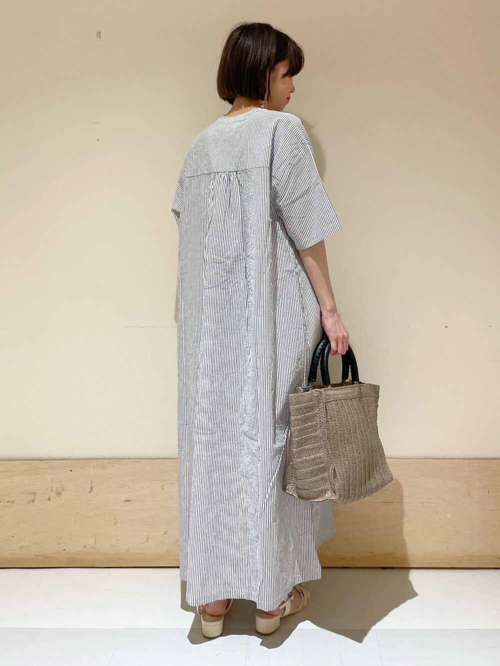 ベージュ系のトートバッグ、ホワイト系のサンダル、ブラック系のワンピースを着用したレディースの夏コーディネートの7枚目の写真