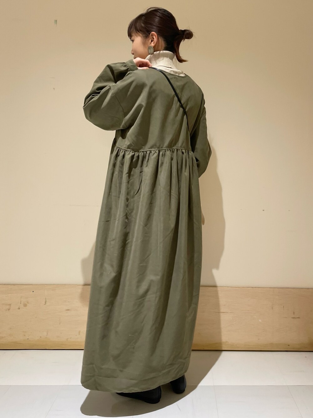 ブラック系のショルダーバッグ、グリーン系のワンピース、グレー系のニット/セーターを着用したレディースの冬コーディネートの2枚目の写真