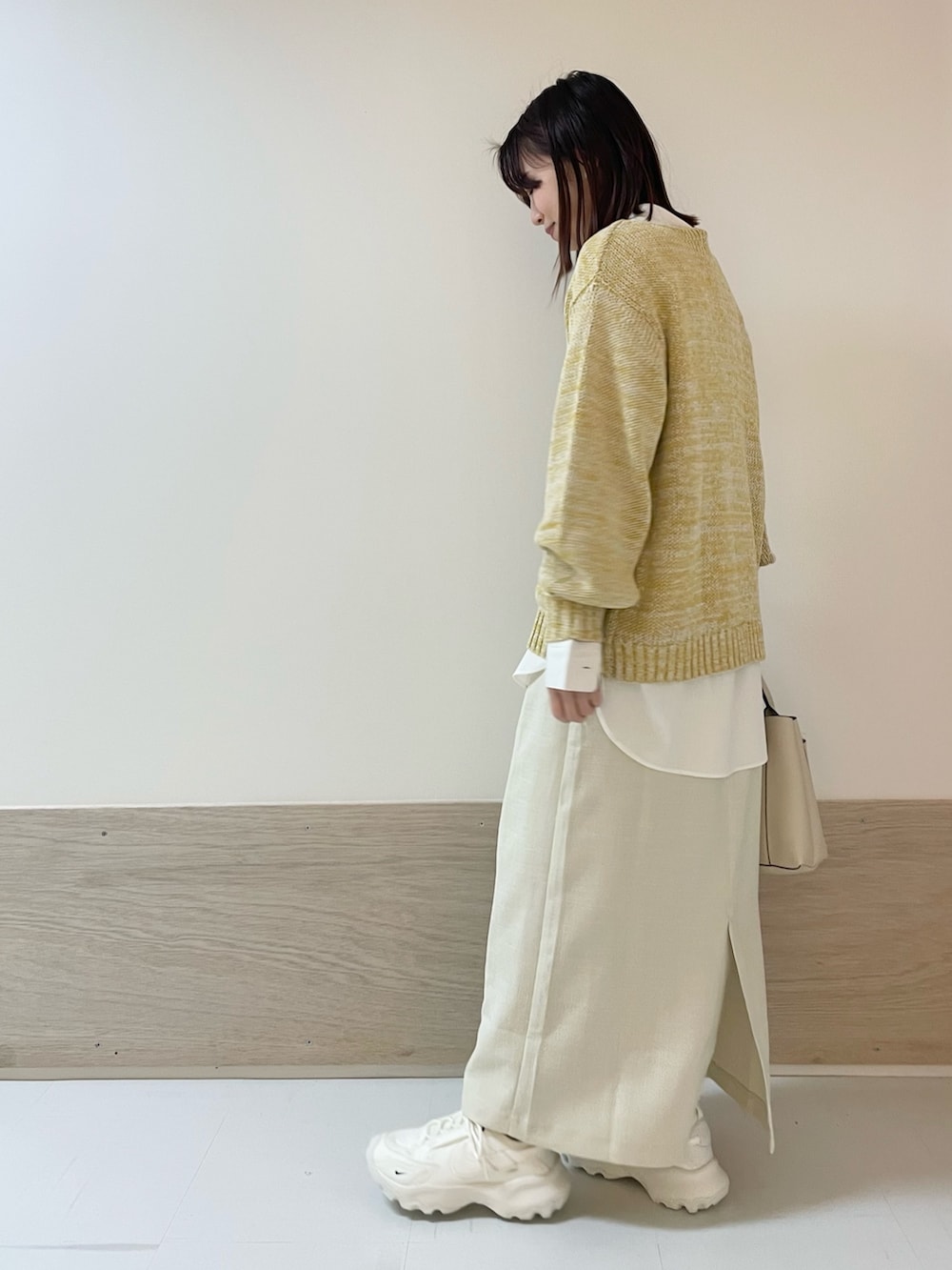 イエロー系のニット/セーター、ホワイト系のシャツ/ブラウス、ホワイト系のスカートを着用したレディースの春コーディネートの5枚目の写真