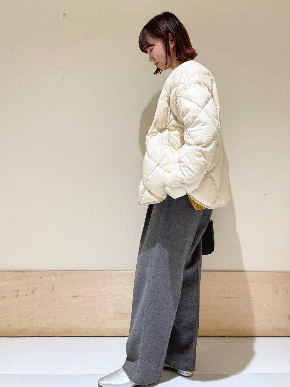 イエロー系のニット/セーター、グレー系のその他パンツ、ブラック系のショルダーバッグを着用したレディースの秋コーディネートの4枚目の写真