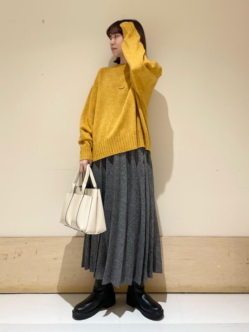 イエロー系のニット/セーター、ブルー系のスカート、ブラック系のブーツを着用したレディースの冬コーディネートの3枚目の写真