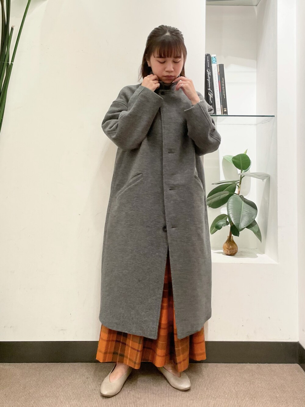 グレー系のニット/セーター、オレンジ系のスカート、グレー系のチェスターコートを着用したレディースの秋コーディネートの2枚目の写真