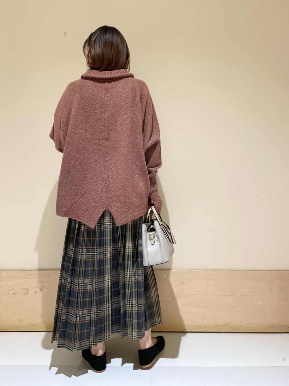 レッド系のニット/セーター、ブラック系のパンプス、グレー系のハンドバッグを着用したレディースの秋コーディネートの6枚目の写真