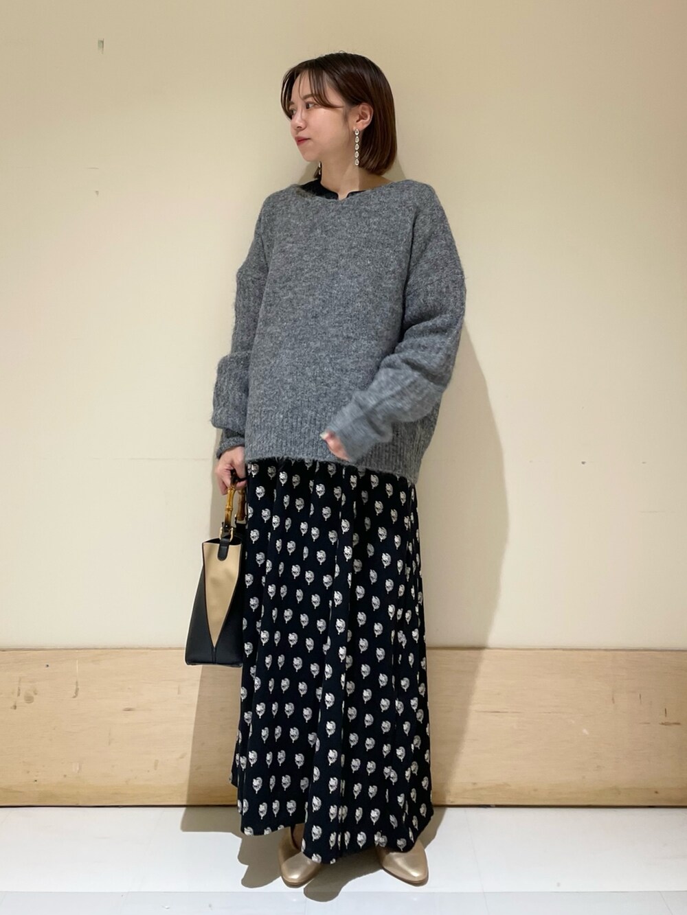 グレー系のニット/セーター、ブラック系のワンピース、ブラック系のハンドバッグを着用したレディースの秋コーディネートの2枚目の写真