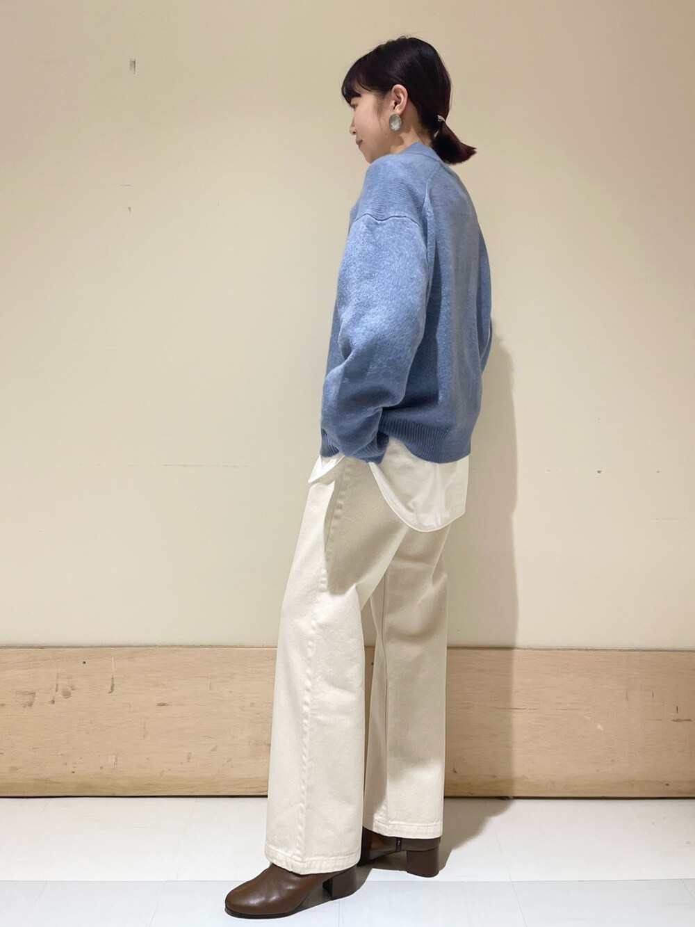 ベージュ系のデニムパンツ、ブルー系のニット/セーター、ホワイト系のショルダーバッグを着用したレディースの冬コーディネートの4枚目の写真