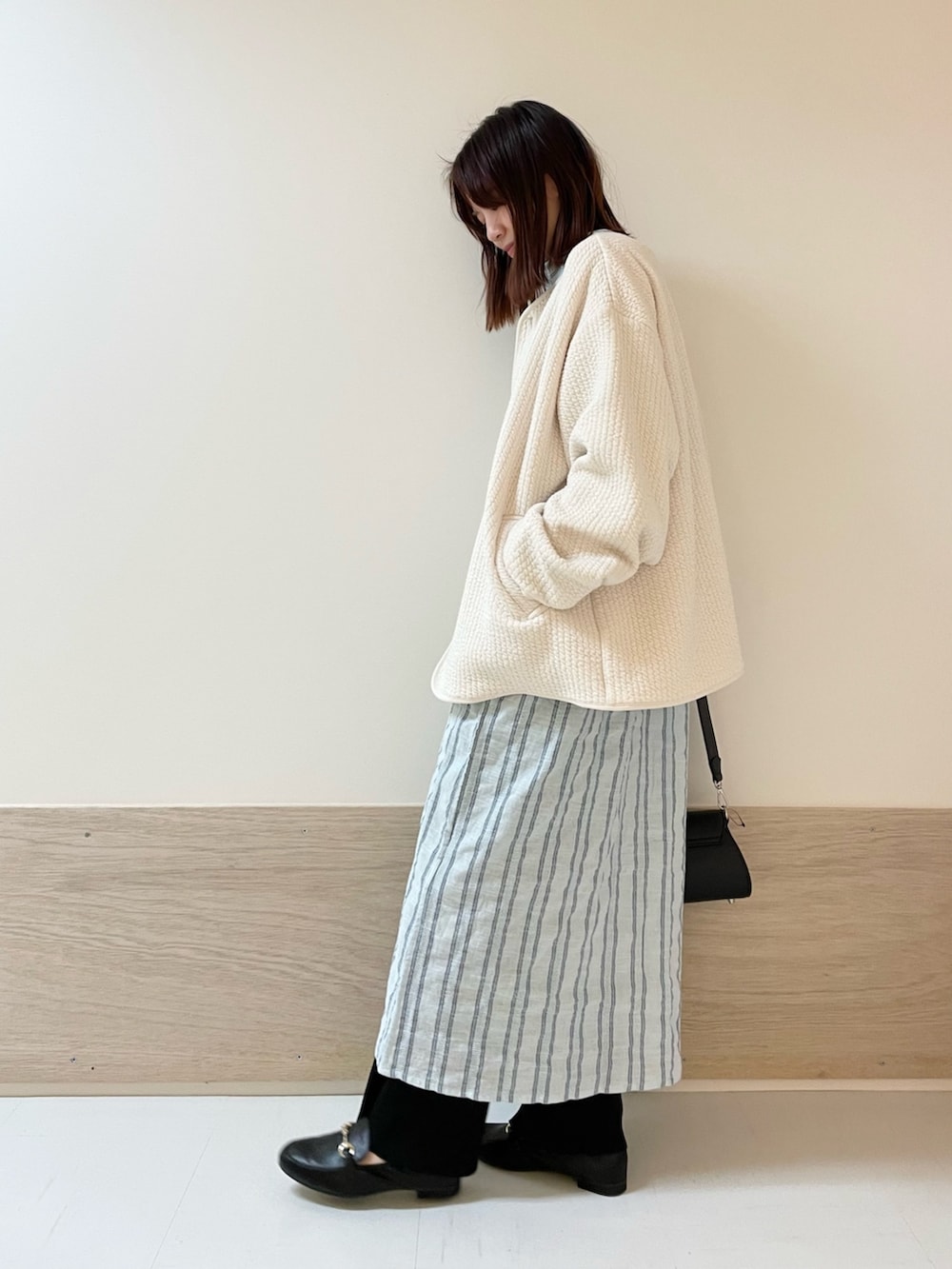 ブラック系のショルダーバッグ、ホワイト系のノーカラージャケット、ブルー系のワンピースを着用したレディースの春コーディネートの5枚目の写真