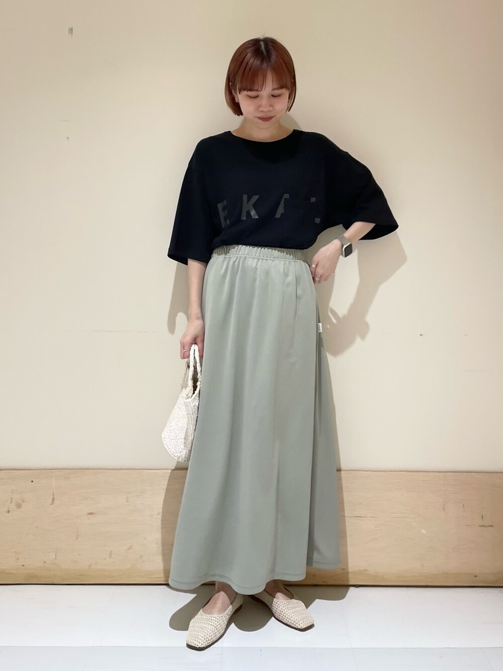 グリーン系のスカート、ブラック系のTシャツ/カットソー、ホワイト系のハンドバッグを着用したレディースの春コーディネートの4枚目の写真