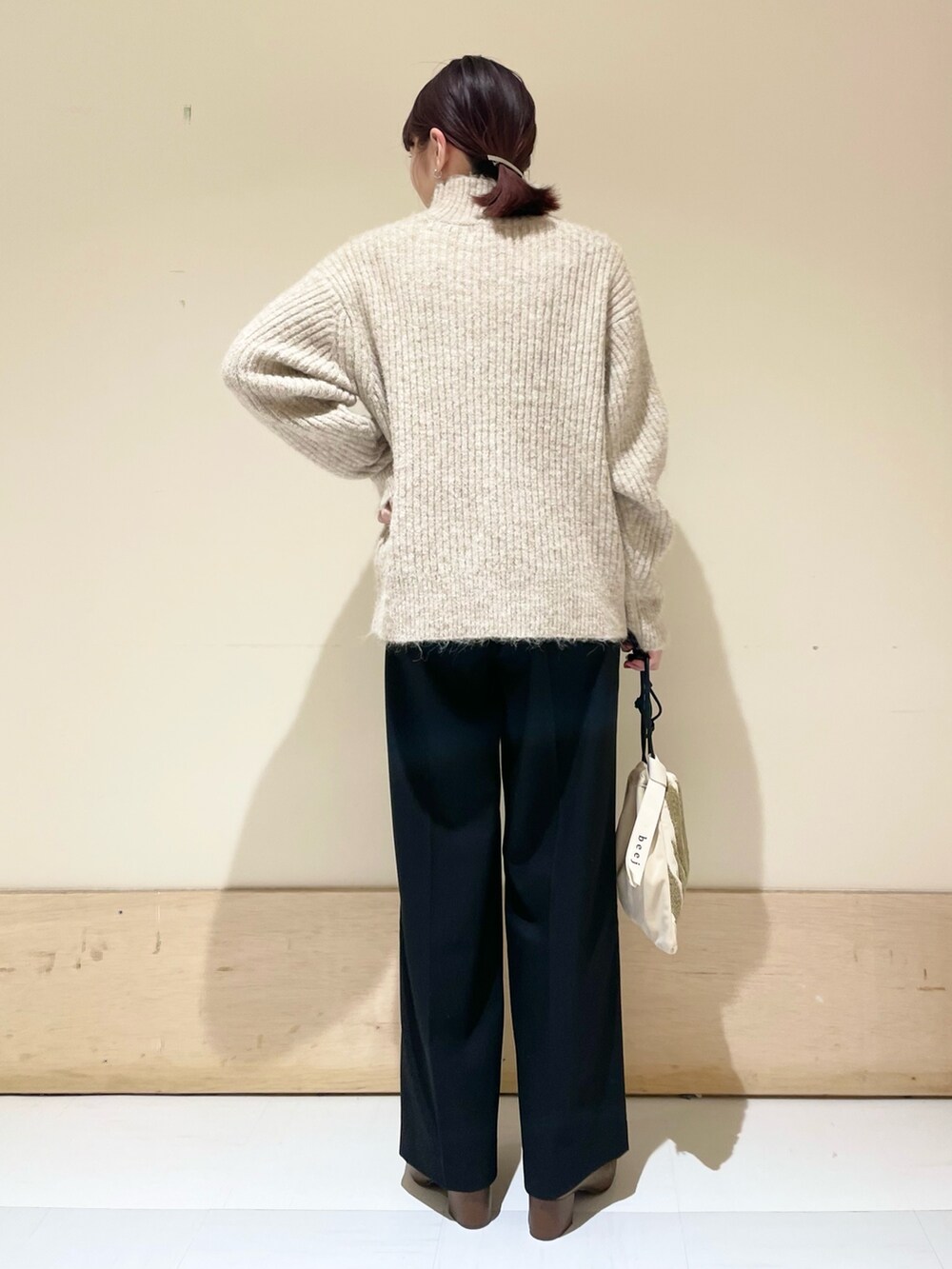 ブラック系のその他パンツ、ベージュ系のニット/セーター、ベージュ系のハンドバッグを着用したレディースの冬コーディネートの6枚目の写真