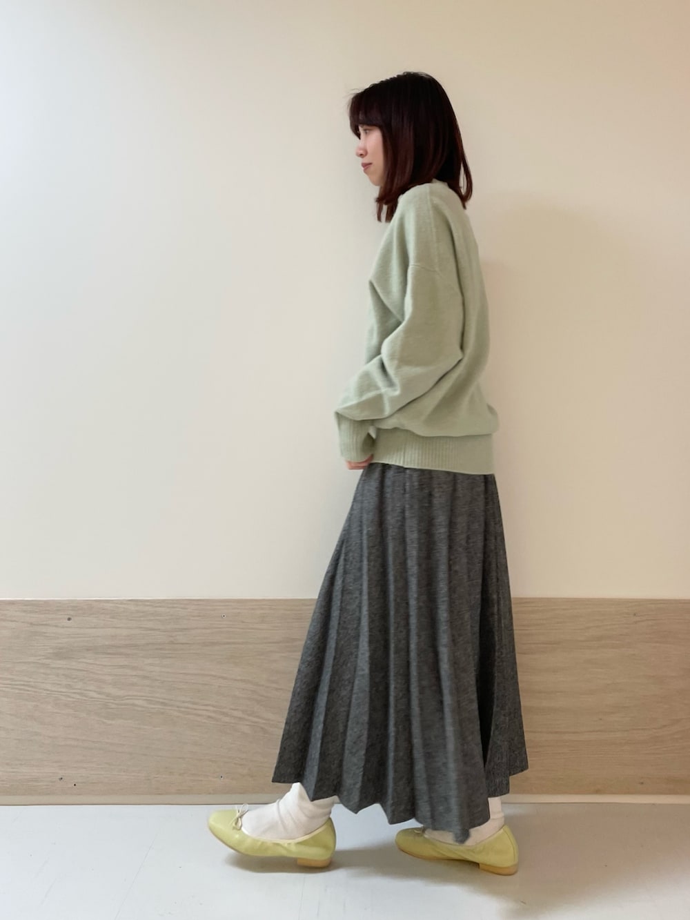 グリーン系のニット/セーター、イエロー系のバレエシューズ、ブルー系のスカートを着用したレディースの冬コーディネートの5枚目の写真