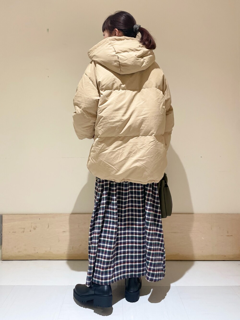 ブラウン系のワンピース、ベージュ系のダウンジャケット/コート、ブラック系のブーツを着用したレディースの冬コーディネートの3枚目の写真