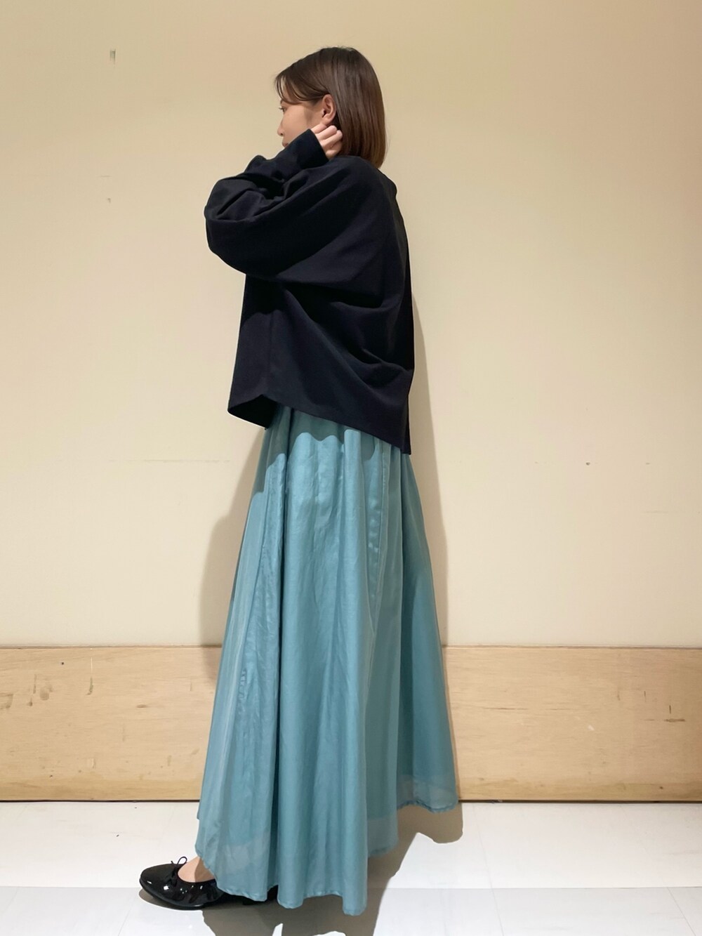 ブラック系のTシャツ/カットソー、グリーン系のスカート、ブラウン系のトートバッグを着用したレディースの秋コーディネートの6枚目の写真