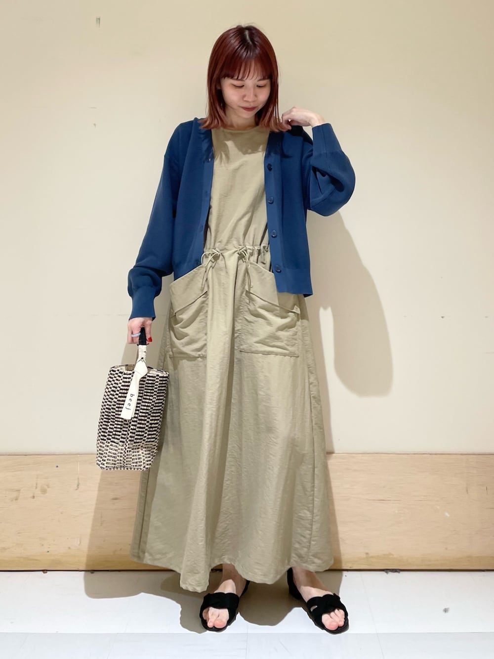 ベージュ系のワンピース、ブルー系のニット/セーター、ブラック系のショルダーバッグを着用したレディースの春コーディネートの3枚目の写真