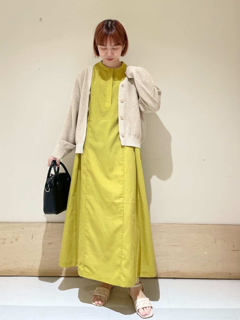 イエロー系のワンピース、ベージュ系のニット/セーター、ブラック系のショルダーバッグを着用したレディースの春コーディネートの3枚目の写真