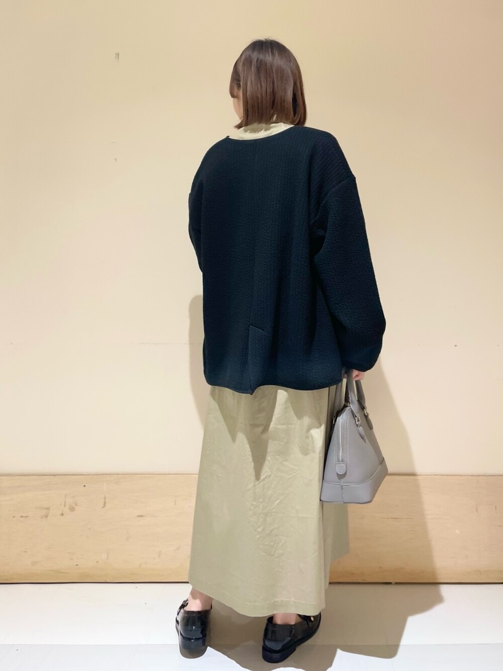 グレー系のショルダーバッグ、ブラック系のノーカラージャケット、ベージュ系のワンピースを着用したレディースの秋コーディネートの6枚目の写真