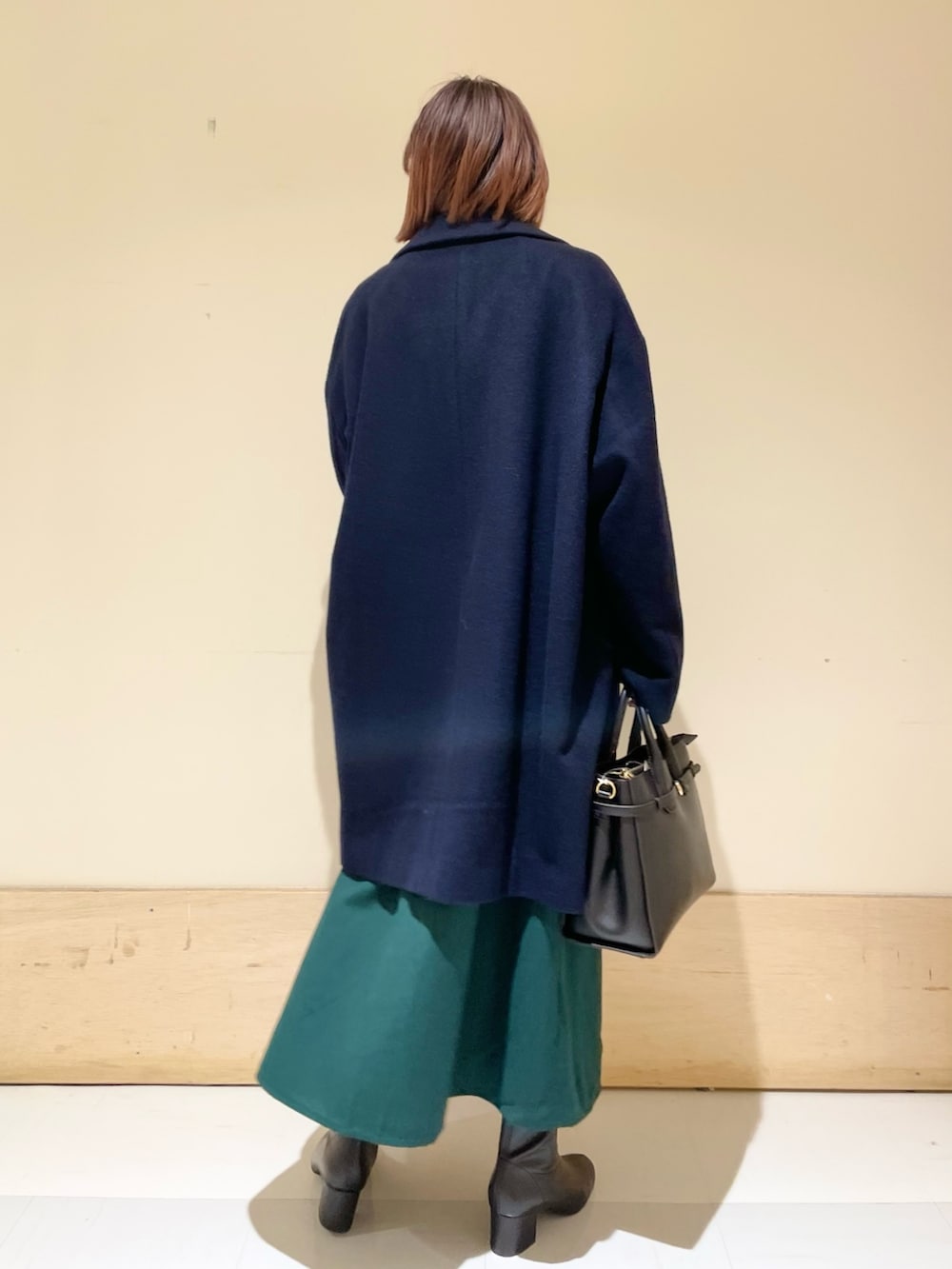 グリーン系のワンピース、ブルー系のピーコート、ブラック系のブーツを着用したレディースの冬コーディネートの6枚目の写真