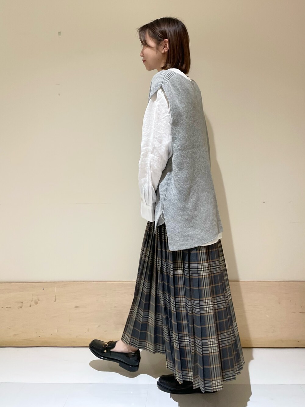 グレー系のベスト、ホワイト系のTシャツ/カットソー、ブラック系のレインシューズを着用したレディースの秋コーディネートの4枚目の写真