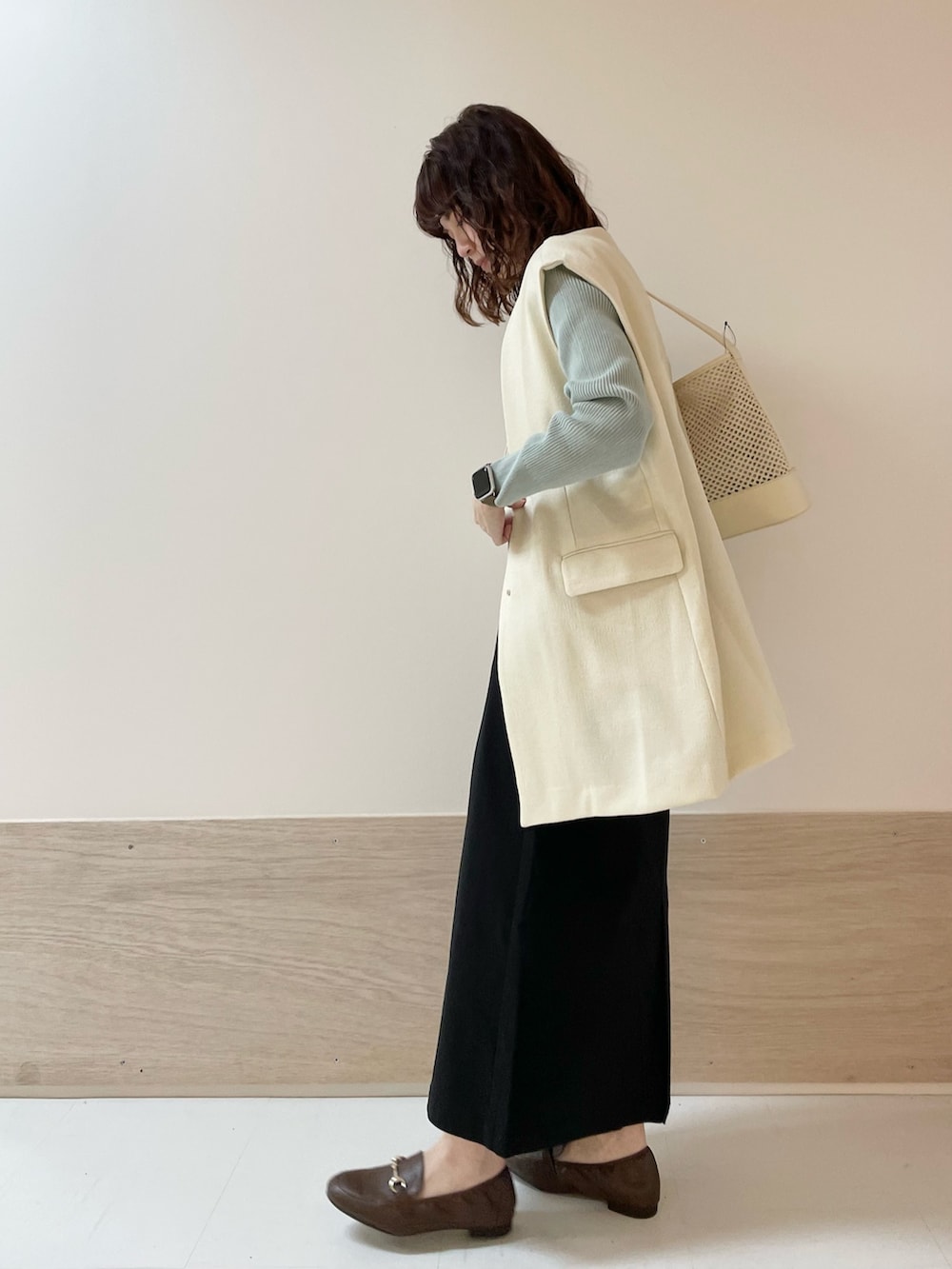 グリーン系のニット/セーター、ホワイト系のその他アウター、ブラック系のスカートを着用したレディースの春コーディネートの4枚目の写真