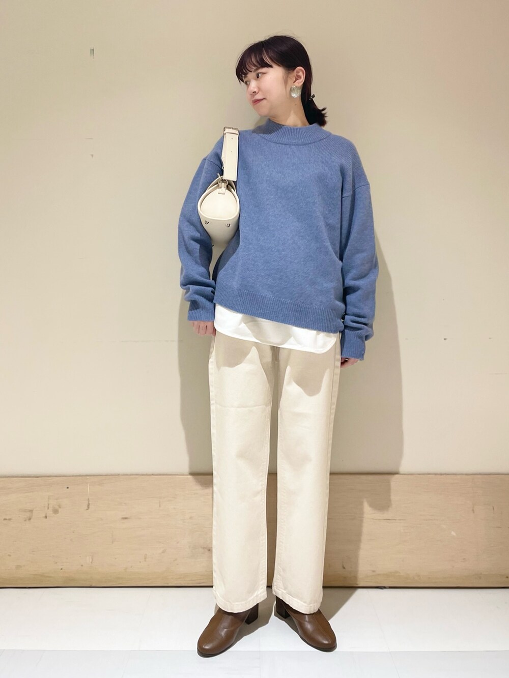 ベージュ系のデニムパンツ、ブルー系のニット/セーター、ホワイト系のショルダーバッグを着用したレディースの冬コーディネートの2枚目の写真