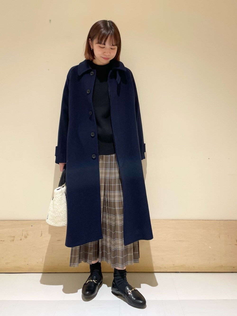 ブラック系のニット/セーター、ホワイト系のショルダーバッグ、ブラウン系のスカートを着用したレディースの冬コーディネートの4枚目の写真