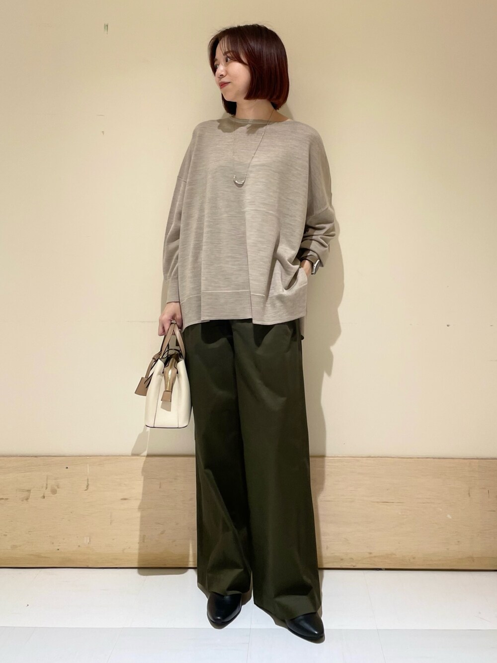 ブラック系のパンプス、ベージュ系のニット/セーター、ホワイト系のハンドバッグを着用したレディースの秋コーディネートの4枚目の写真