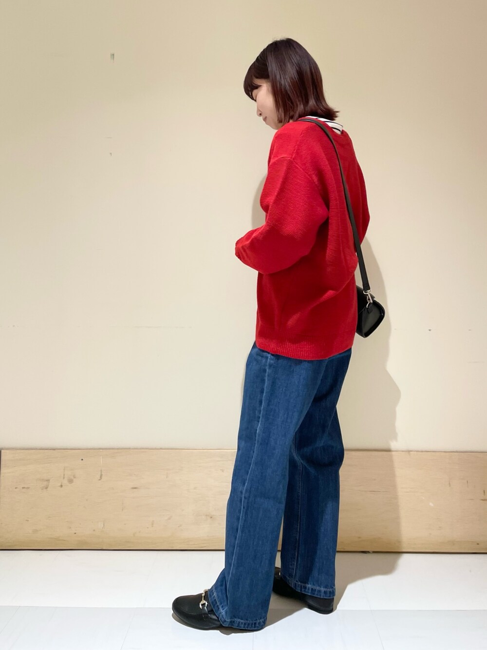 ブラック系のショルダーバッグ、レッド系のカーディガン/ボレロ、ホワイト系のTシャツ/カットソーを着用したレディースの冬コーディネートの4枚目の写真