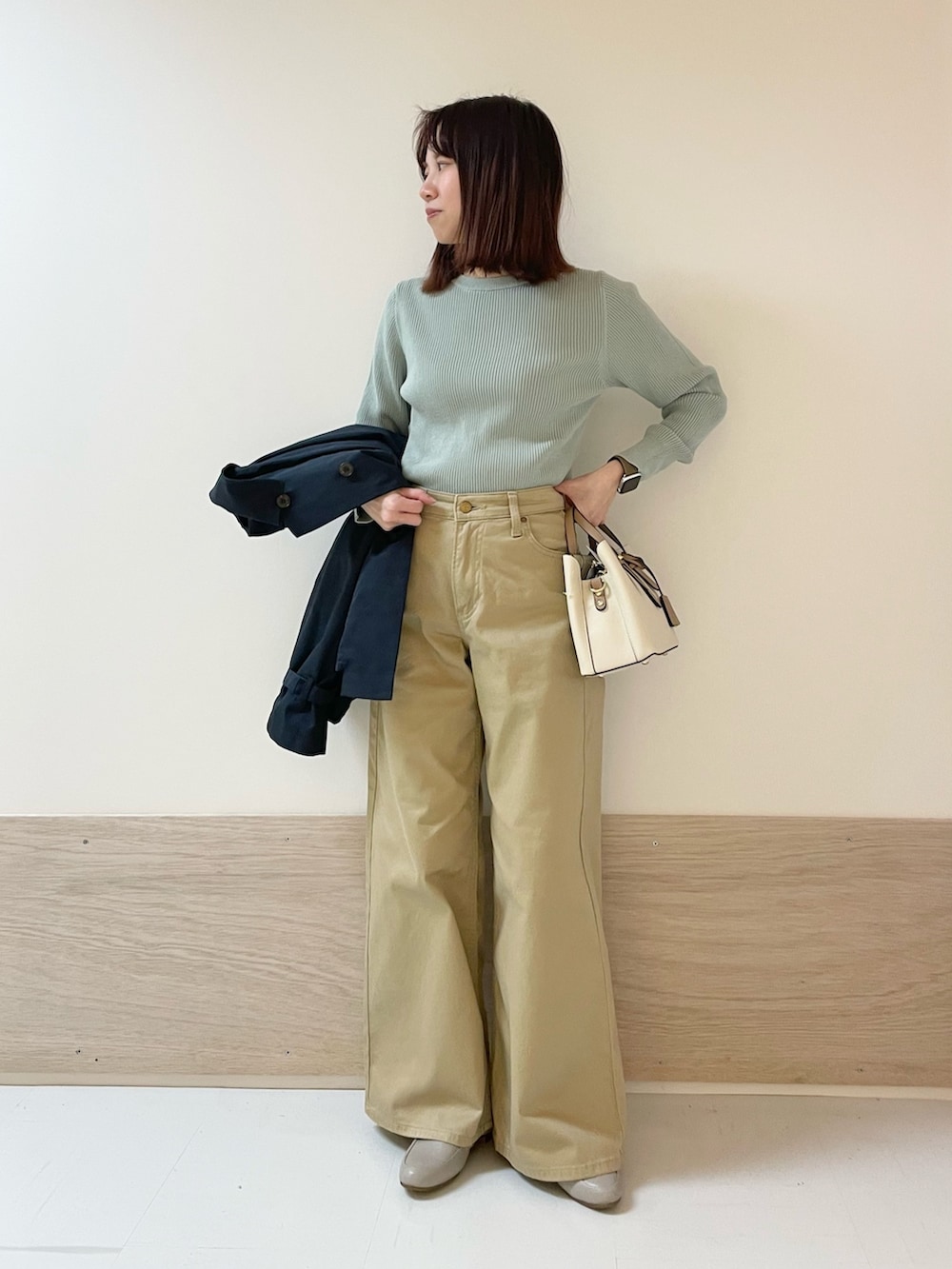 ブルー系のトレンチコート、グリーン系のニット/セーター、ベージュ系のその他パンツを着用したレディースの春コーディネートの6枚目の写真