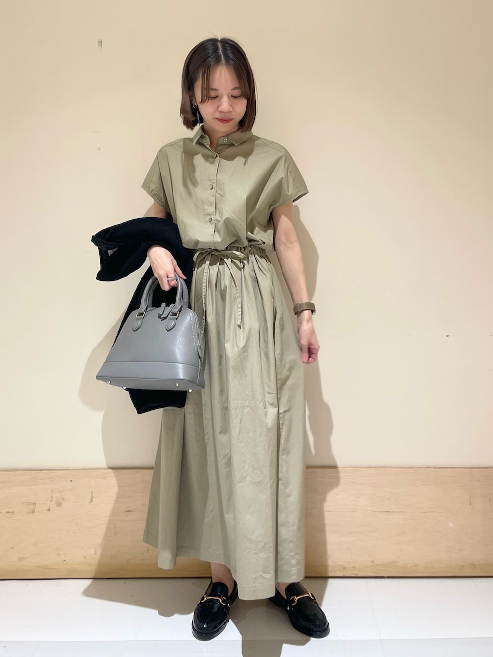 グレー系のショルダーバッグ、ブラック系のノーカラージャケット、ベージュ系のワンピースを着用したレディースの秋コーディネートの7枚目の写真