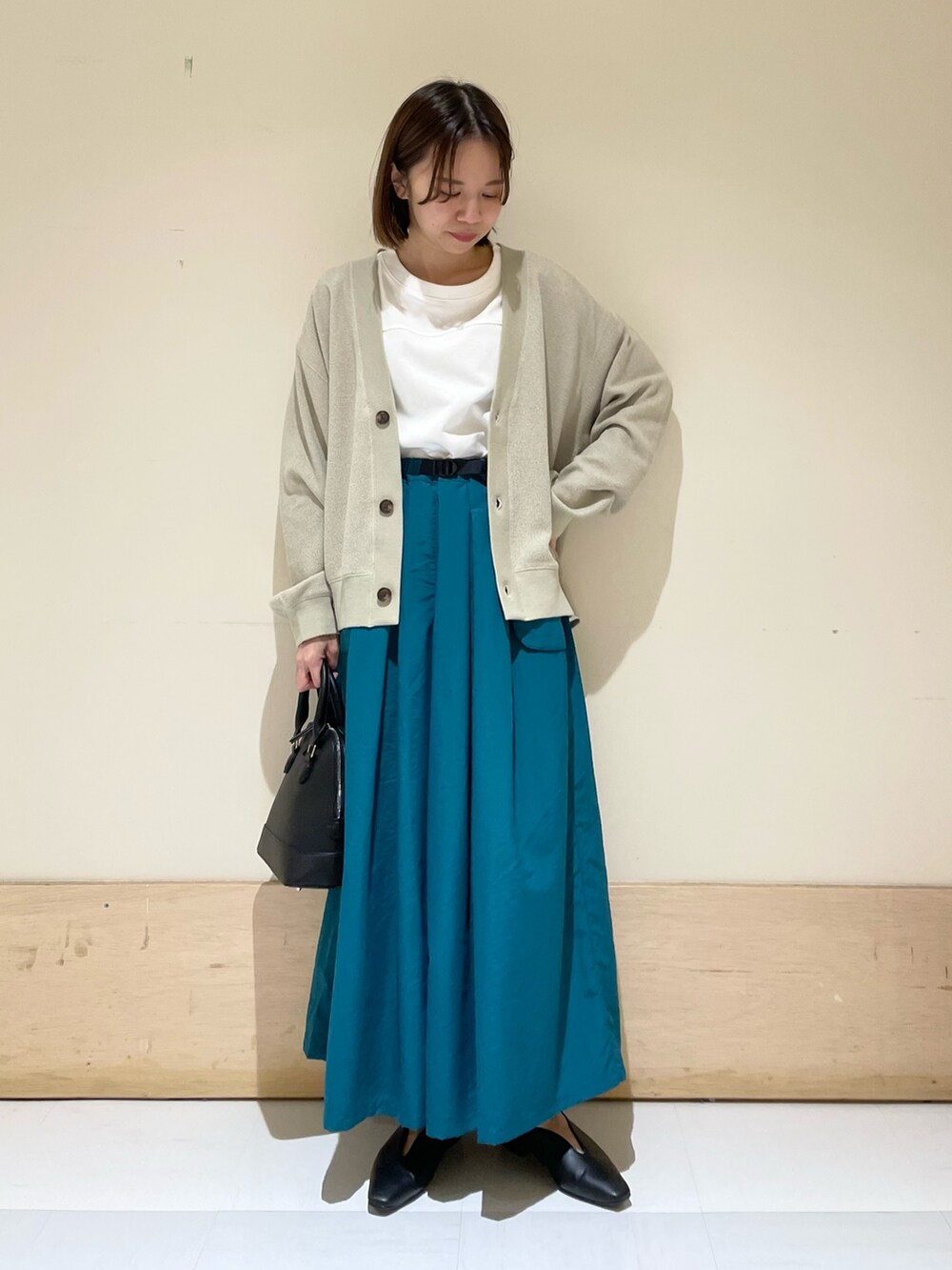 ベージュ系のカーディガン/ボレロ、ホワイト系のTシャツ/カットソー、ブラック系のショルダーバッグを着用したレディースの秋コーディネートの3枚目の写真