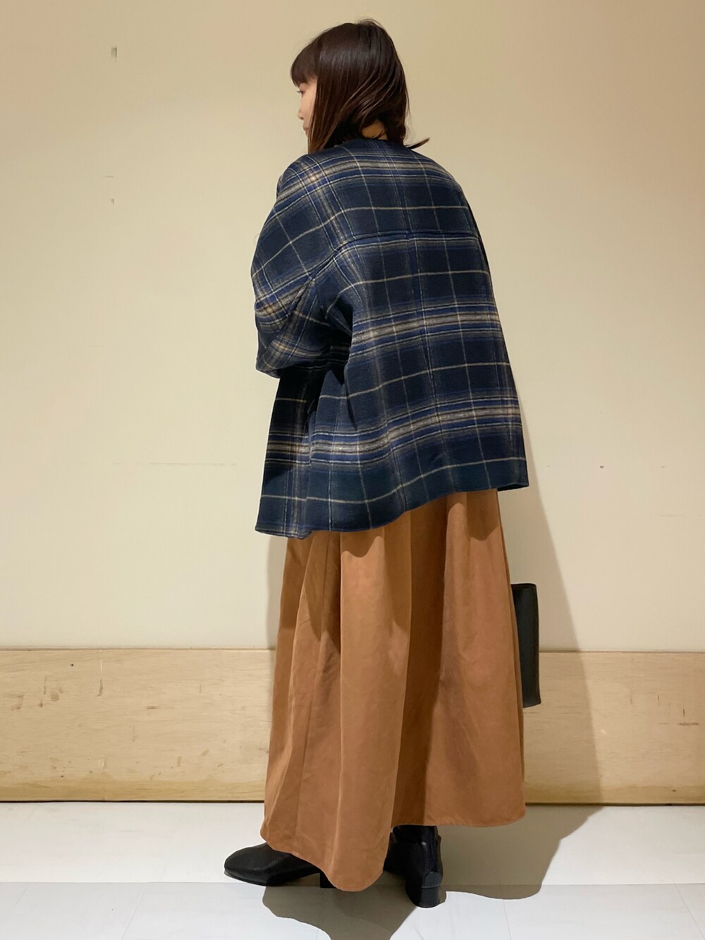 ブルー系のノーカラージャケット、イエロー系のワンピース、ブラック系のブーツを着用したレディースの冬コーディネートの2枚目の写真