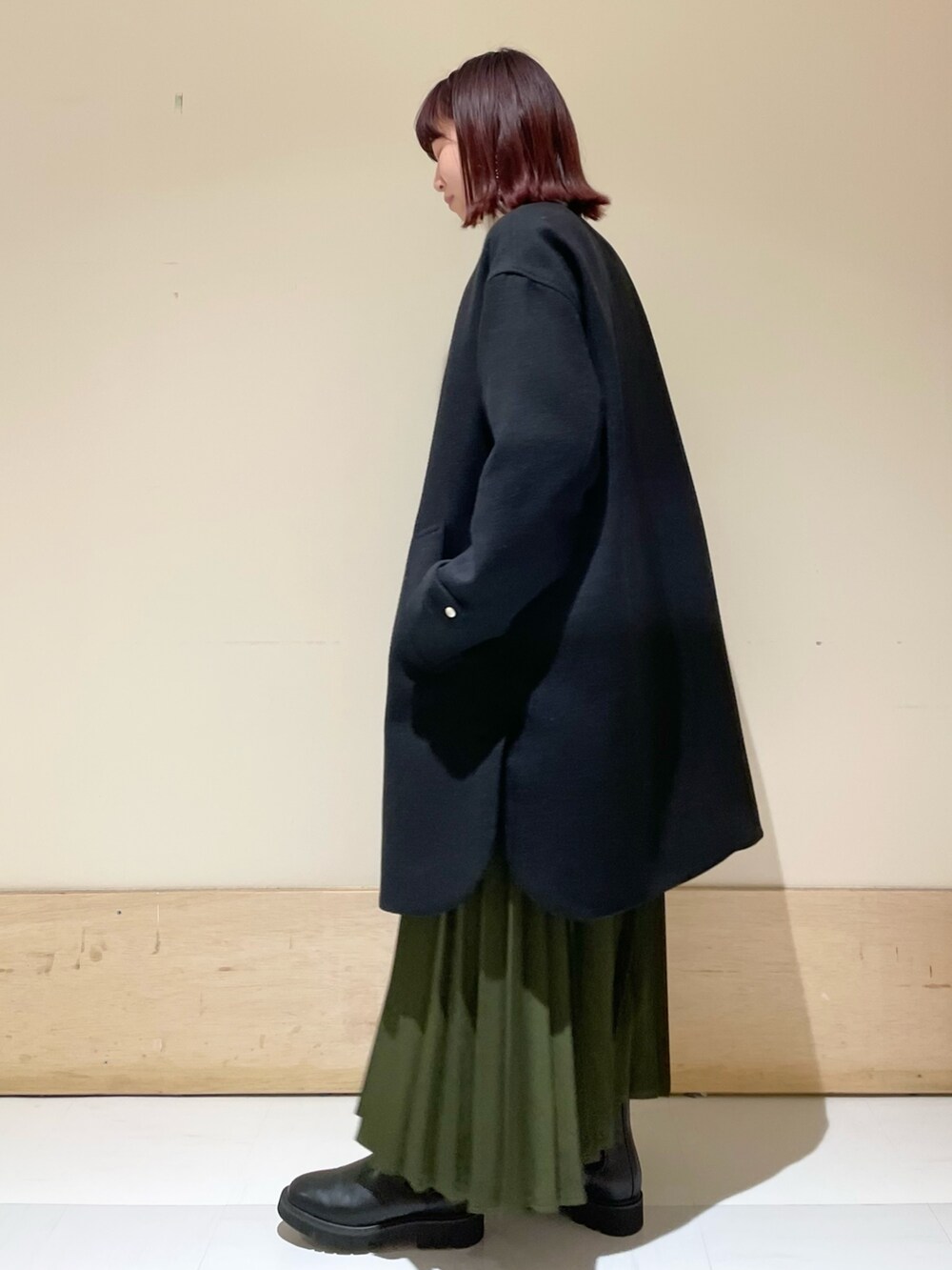 ブラック系のその他アウター、ブラック系のブーツ、グリーン系のスカートを着用したレディースの冬コーディネートの3枚目の写真