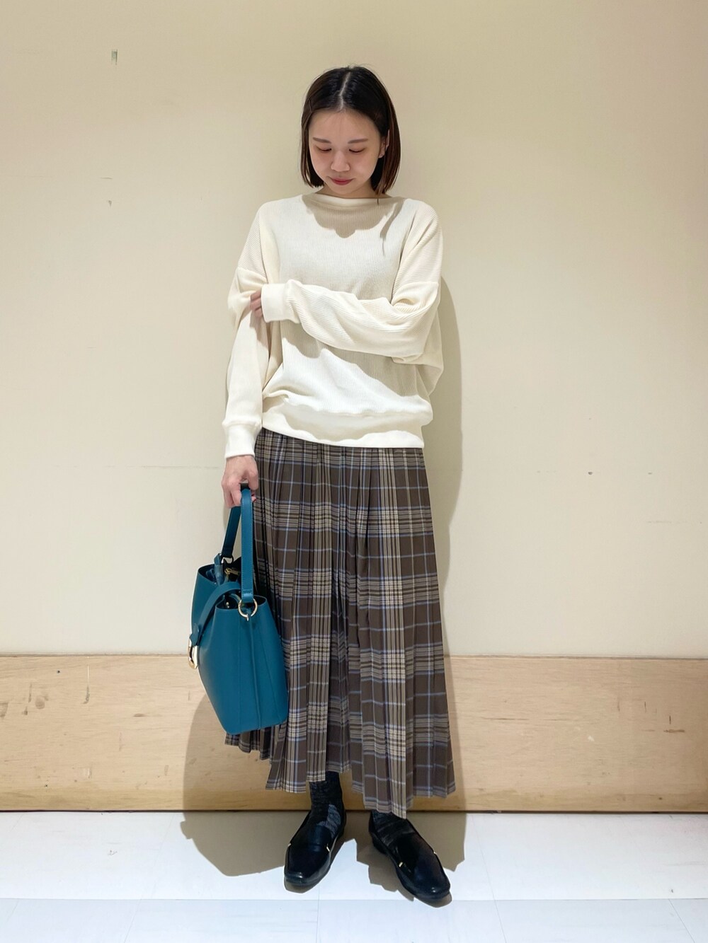 ブルー系のハンドバッグ、ブラック系のローファー、ベージュ系のTシャツ/カットソーを着用したレディースの秋コーディネートの4枚目の写真