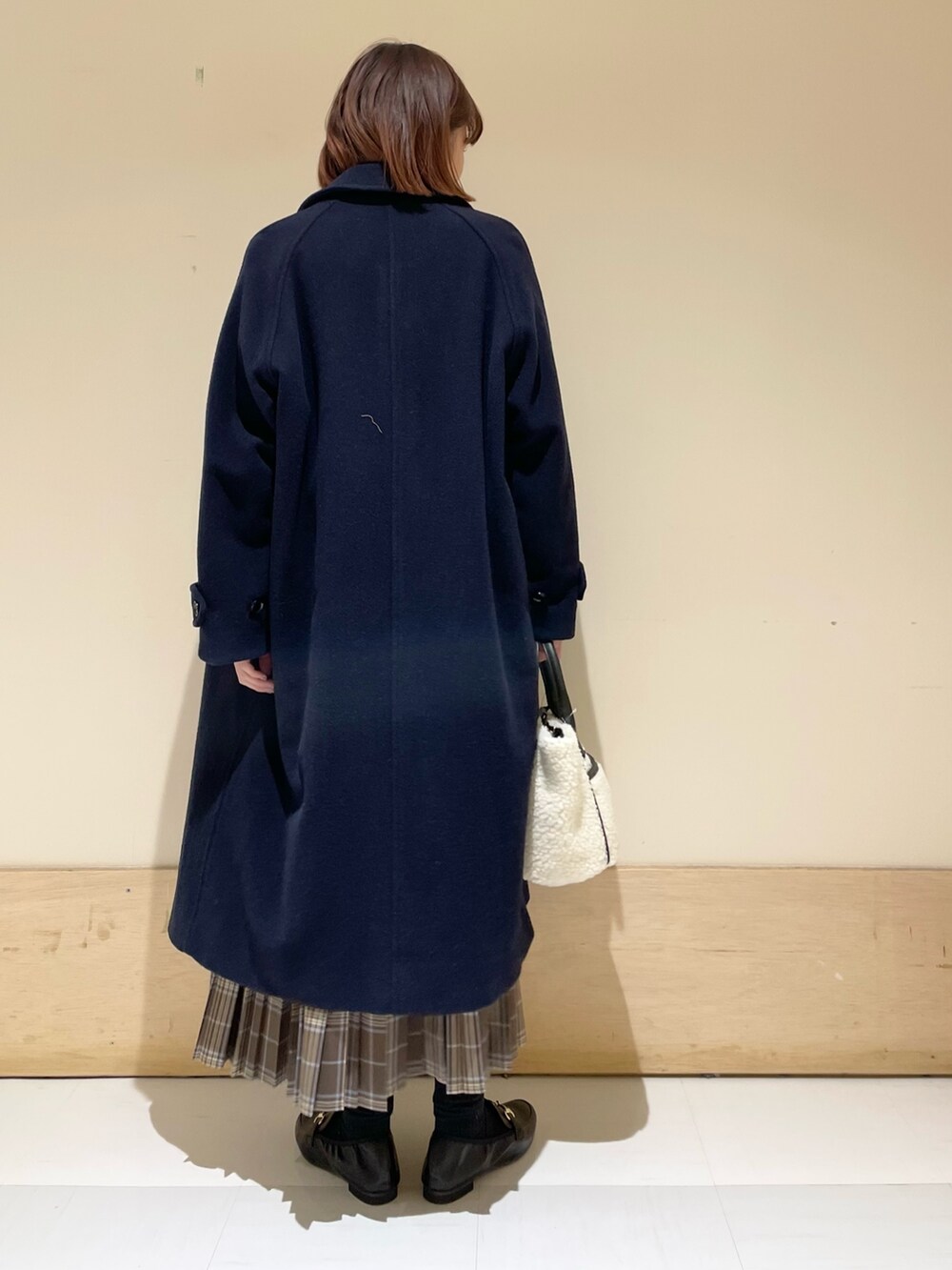 ブラック系のニット/セーター、ホワイト系のショルダーバッグ、ブラウン系のスカートを着用したレディースの冬コーディネートの7枚目の写真