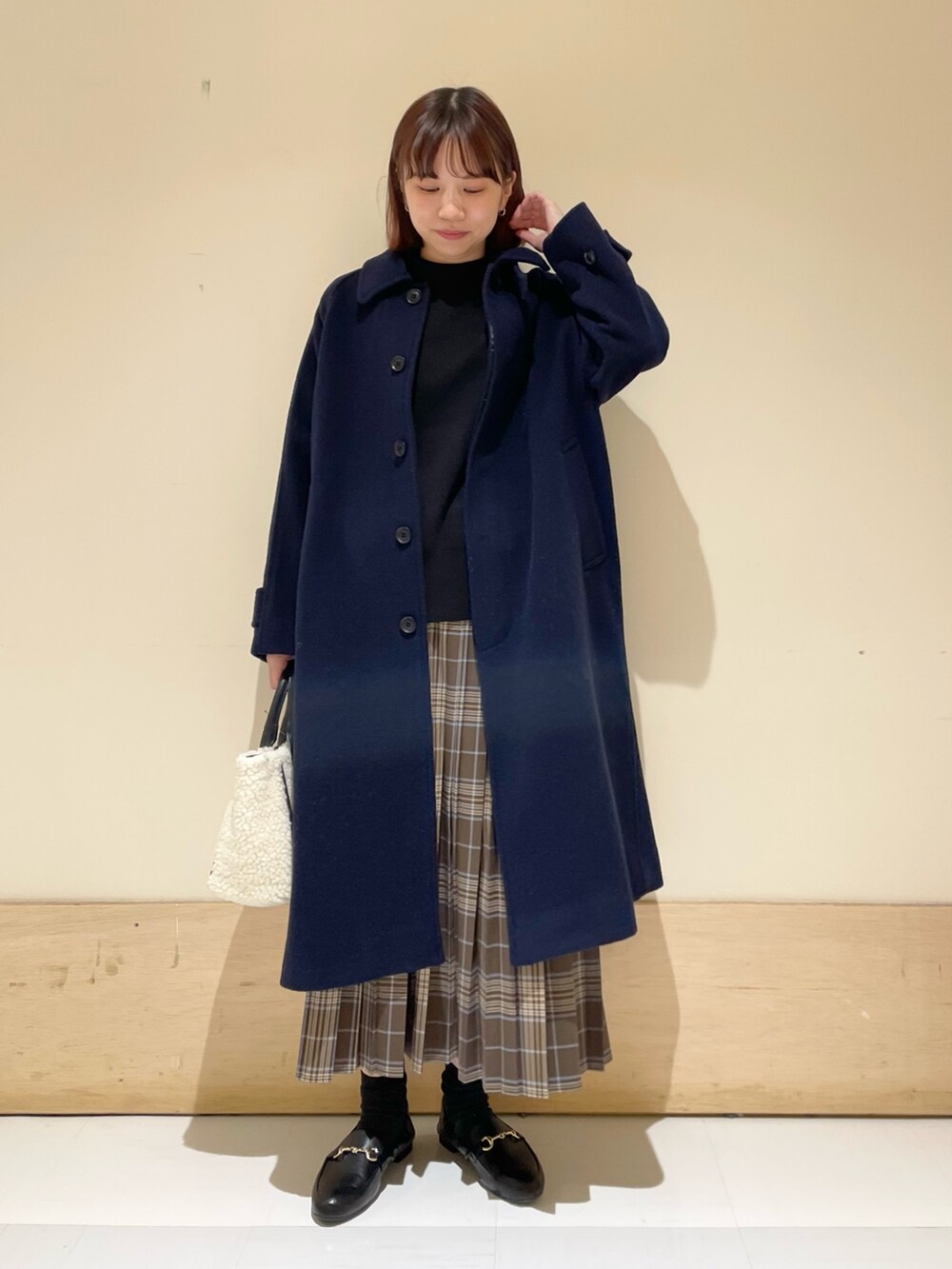 ブラック系のニット/セーター、ホワイト系のショルダーバッグ、ブラウン系のスカートを着用したレディースの冬コーディネートの2枚目の写真