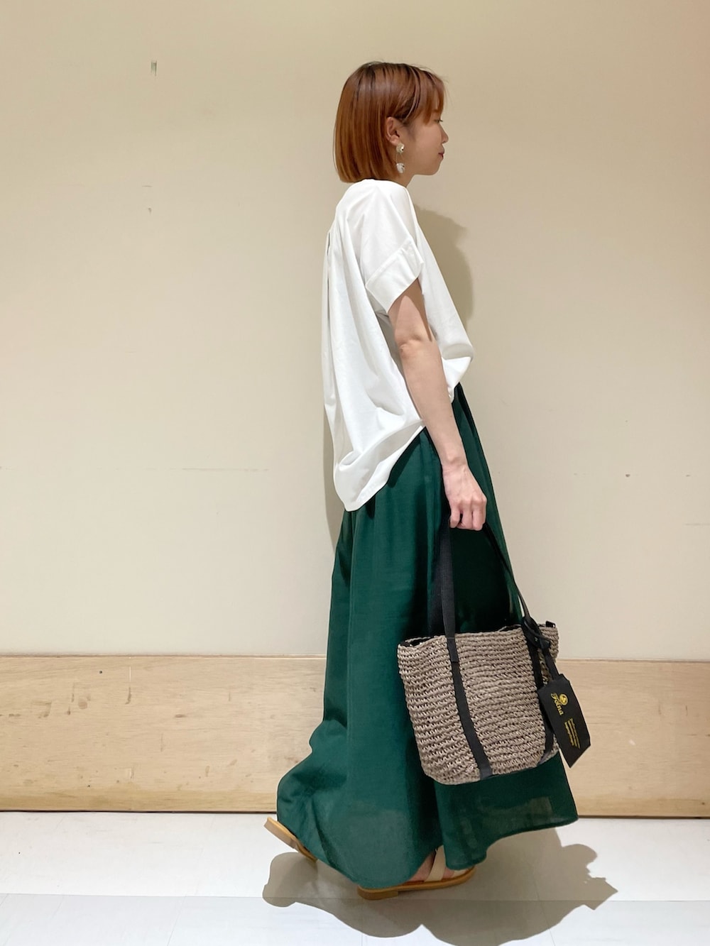 ホワイト系のTシャツ/カットソー、グレー系のトートバッグ、グリーン系のスカートを着用したレディースの夏コーディネートの6枚目の写真