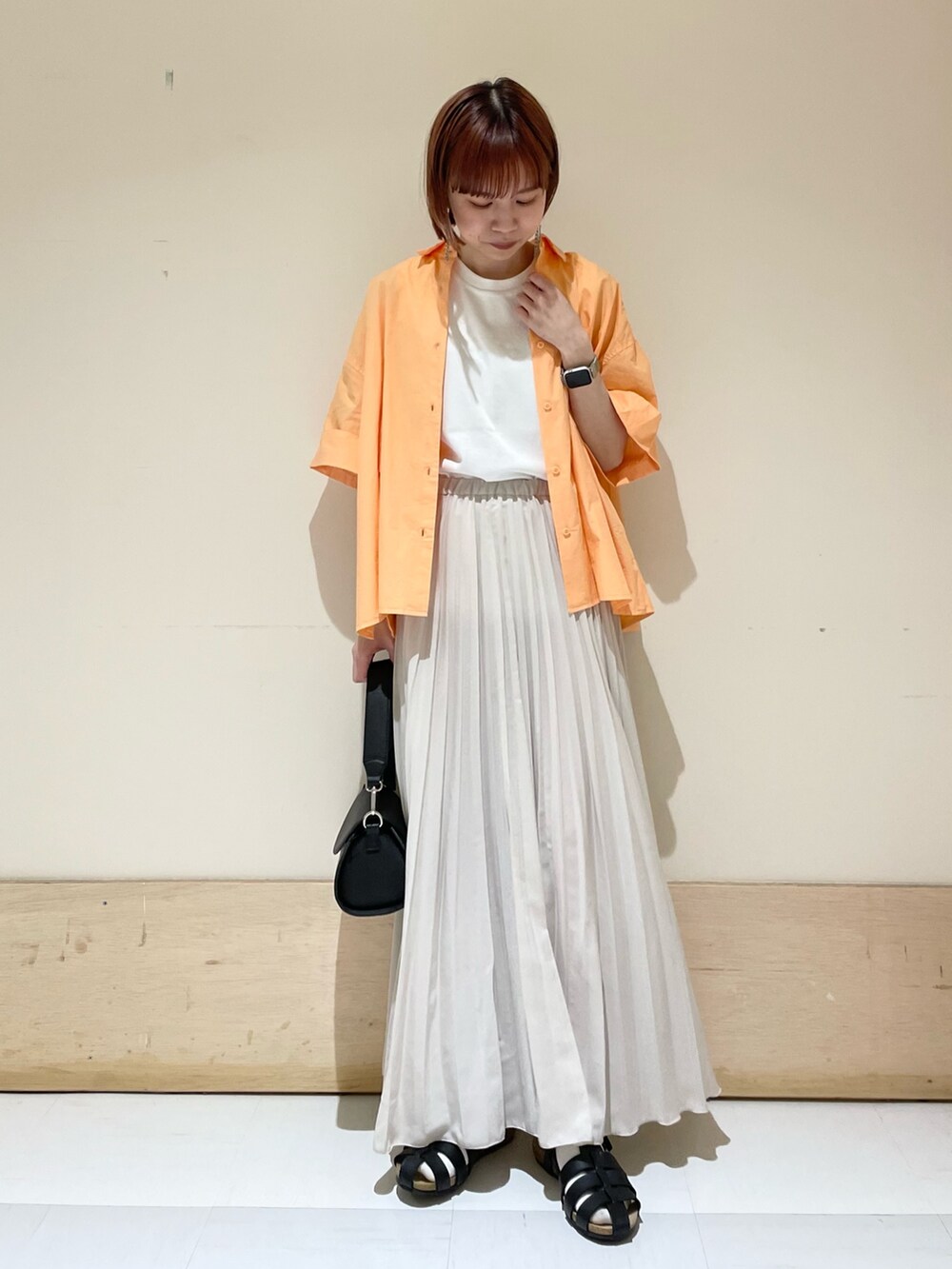 ブラック系のショルダーバッグ、ブラック系のサンダル、ホワイト系のスカートを着用したレディースの春コーディネートの2枚目の写真