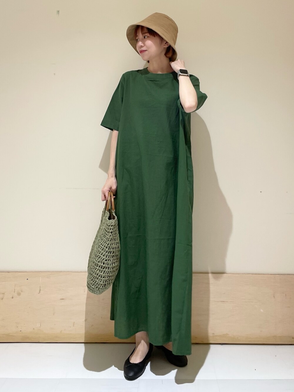グリーン系のワンピース、ブラック系のバレエシューズ、グリーン系のかごバッグを着用したレディースの春コーディネートの2枚目の写真